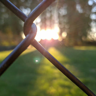 sunset through the link of a chainlink fence
