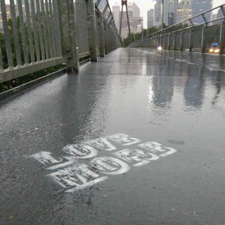 white stencil on pavement, "love more"